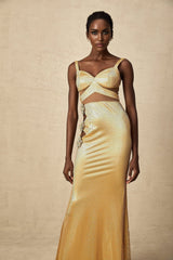 Woman wearing long gold maxi dress with floral cutout pattern and sleeveless design