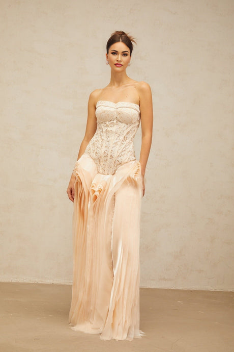 Woman wearing long ivory lace maxi dress with corset bodice and layered skirt in neutral tones