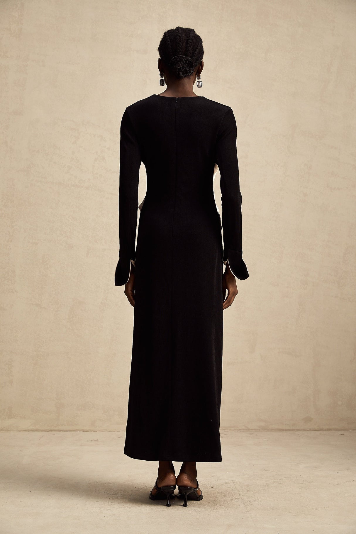 Woman wearing long maxi dress with contrasting colors and vneck featuring a decorative bow detail