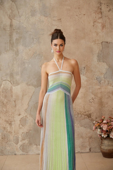 Woman wearing long metallic knit backless maxi dress with shimmering fabric and elegant drape