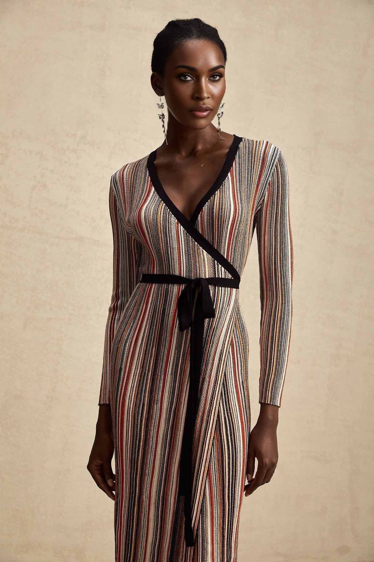 Woman wearing long metallic stripe midi dress with wrap design