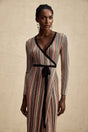 Woman wearing long metallic stripe midi dress with wrap design