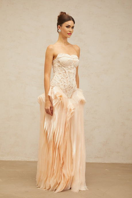 Woman wearing long neutral colored maxi dress with lace overlay and corset style bodice