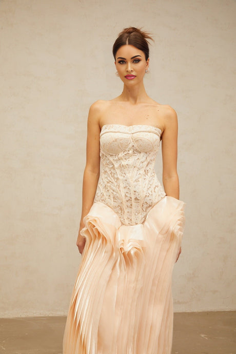 Woman wearing long neutral colored maxi dress with lace overlay and corset style bodice