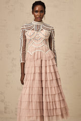 Woman wearing long pink gown with tiered skirt and beaded details semi sheer fabric floor length dress formal evening wear