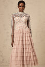 Woman wearing long pink gown with tiered skirt and beaded details semi sheer fabric floor length dress formal evening wear