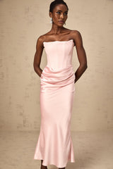 Woman wearing long pink offshoulder maxi dress with flowing skirt standing outdoors