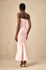 Woman wearing long pink offshoulder maxi dress with flowy skirt standing outdoors