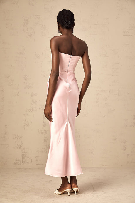 Woman wearing long pink offshoulder maxi dress with flowy skirt standing outdoors