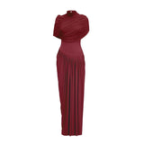Woman wearing long red asymmetric pleated maxi dress with flowing skirt