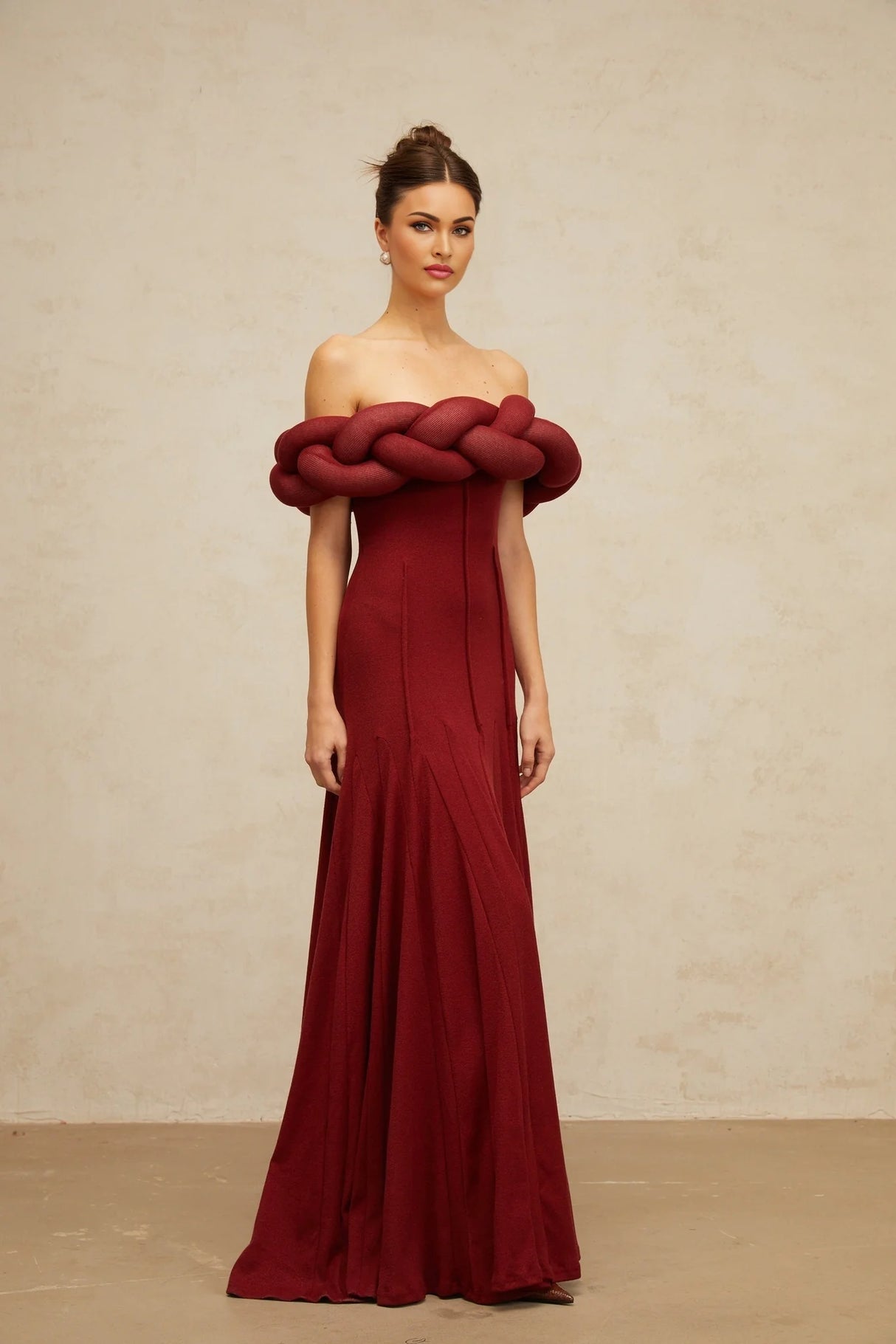 Woman wearing long red knit maxi dress with braided design detail