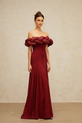 Woman wearing long red knit maxi dress with braided design detail