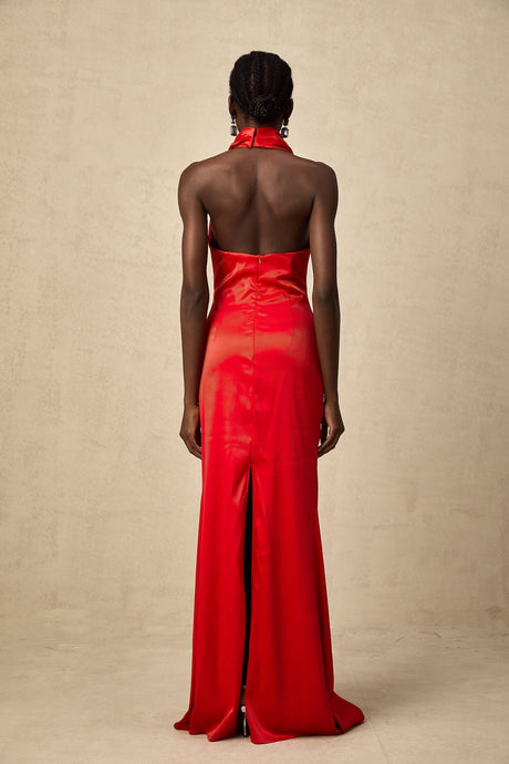 Woman wearing long red satin maxi dress with halter neckline and draped design