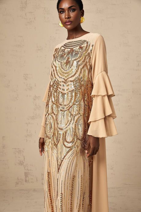 Woman wearing long sequined tulle dress with ruffle sleeves and flowing maxi skirt in elegant pose