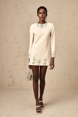 Woman wearing long sleeved mini dress in neutral color with crystal embellishments