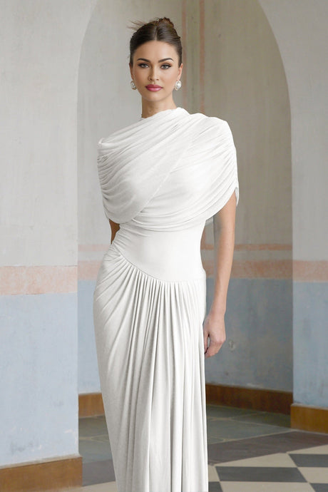 Woman wearing long white asymmetric pleated maxi dress with one shoulder strap