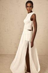 Woman wearing long white dress with one shoulder strap and gathered fabric details flowing to floor length