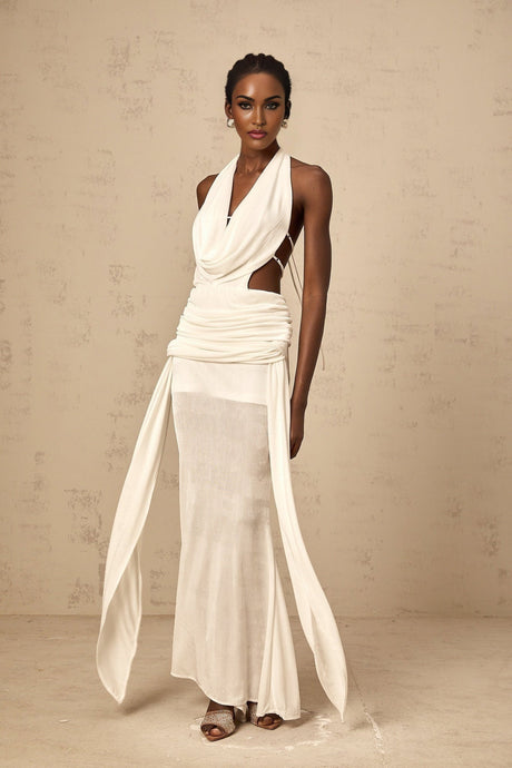 Woman wearing long white halterneck maxi dress with open back design standing in relaxed pose