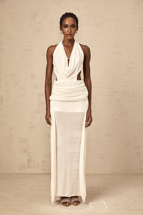 Woman wearing long white halterneck maxi dress with open back standing against plain background