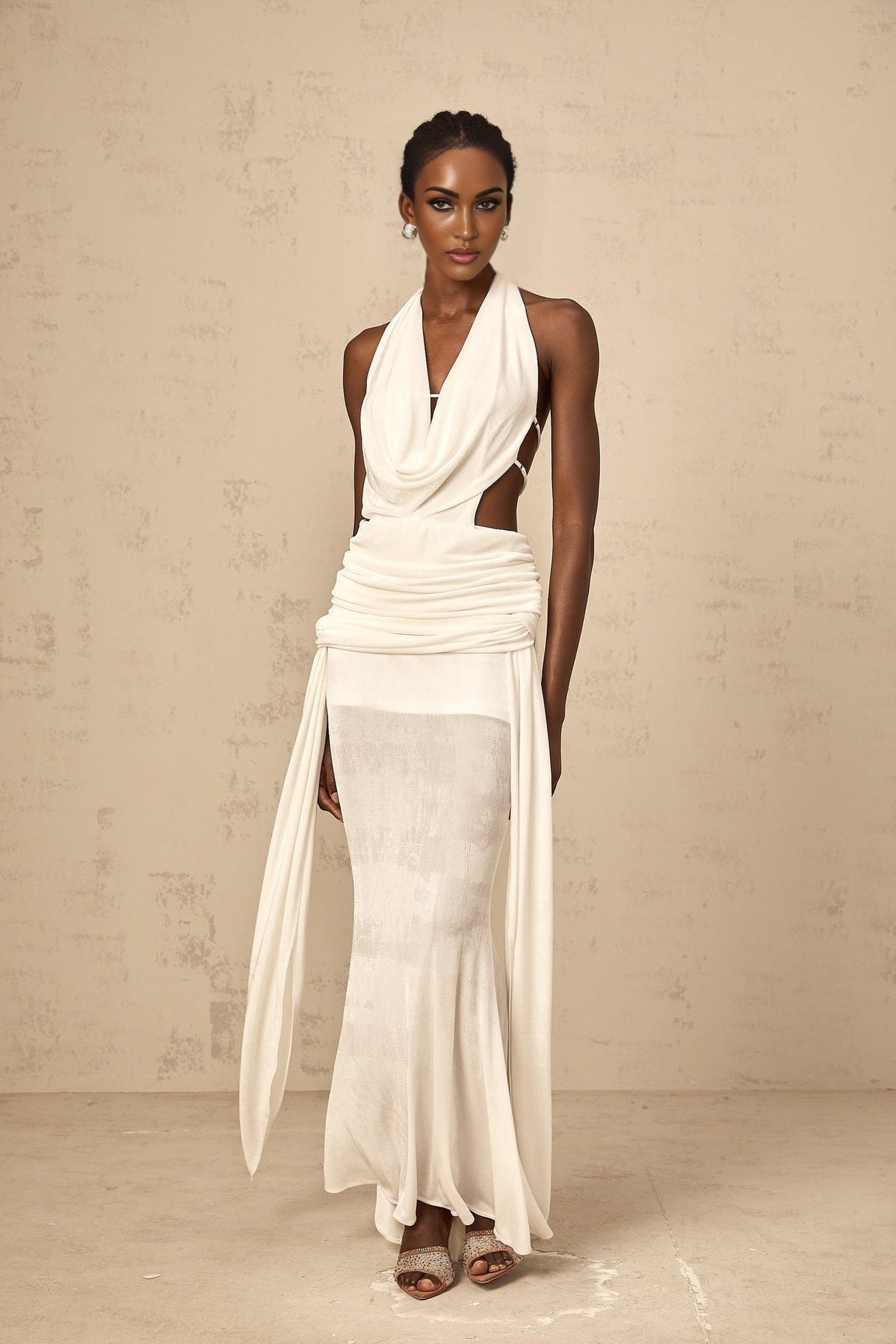 Woman wearing long white halterneck maxi dress with open back standing in relaxed pose