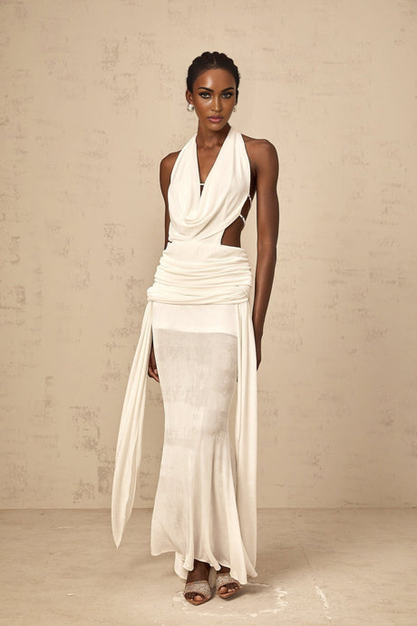 Woman wearing long white halterneck maxi dress with open back standing in relaxed pose