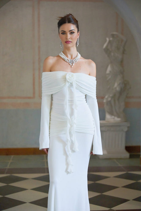 Woman wearing long white knit dress with glittery floral appliques standing in relaxed pose