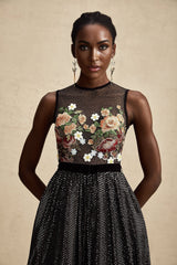 Woman wearing long white maxi dress with colorful floral embroidery details and delicate embellishments