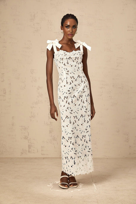 Woman wearing long white maxi dress with colorful floral embroidery details