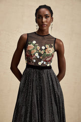 Woman wearing long white maxi dress with colorful floral embroidery embellishments