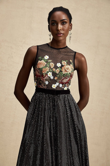 Woman wearing long white maxi dress with colorful floral embroidery embellishments