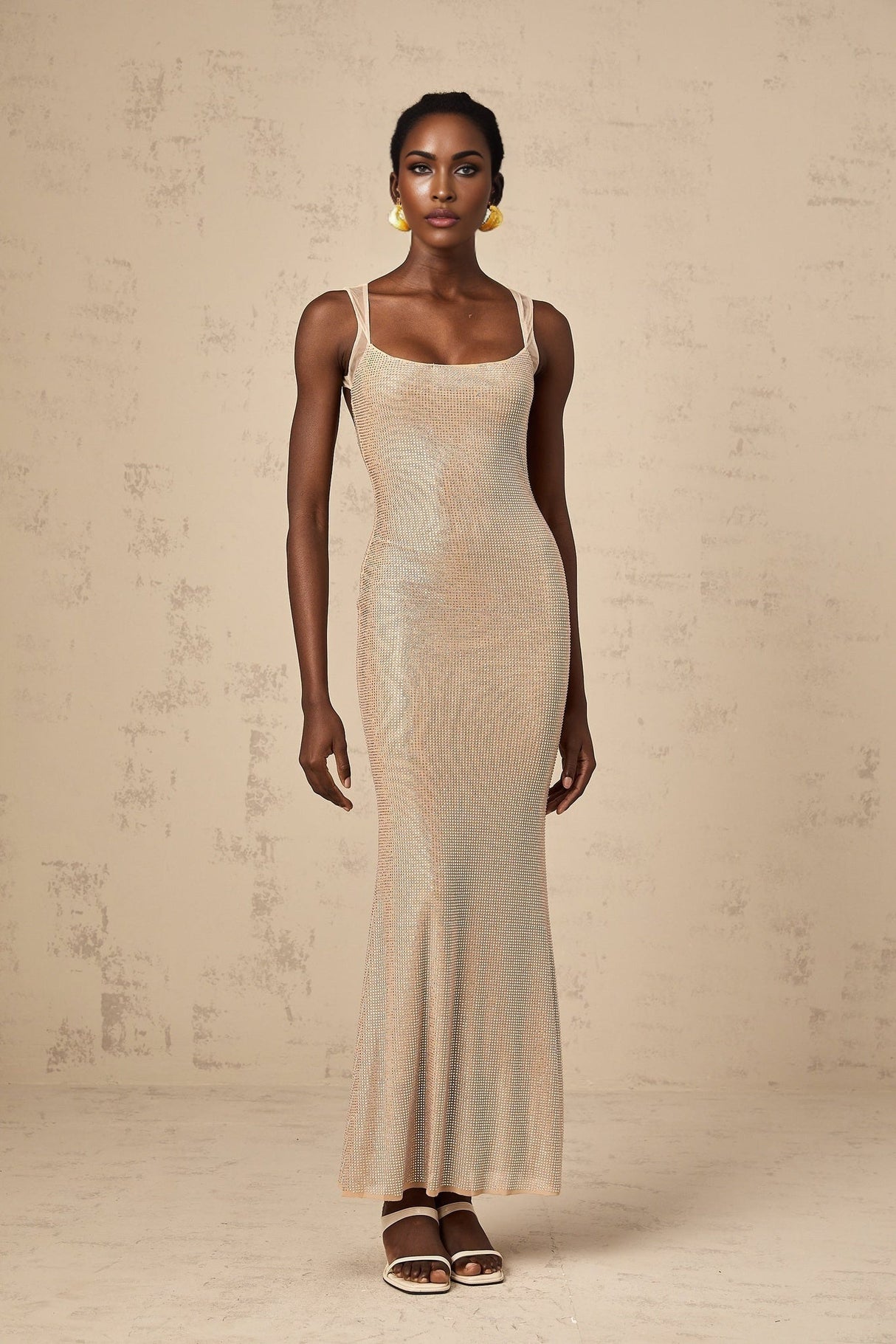 Woman wearing long white maxi dress with crystal embellishments and open back design