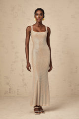 Woman wearing long white maxi dress with crystal embellishments and open back design