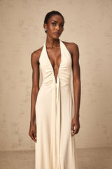 Woman wearing long white maxi dress with deep V neckline and draped design