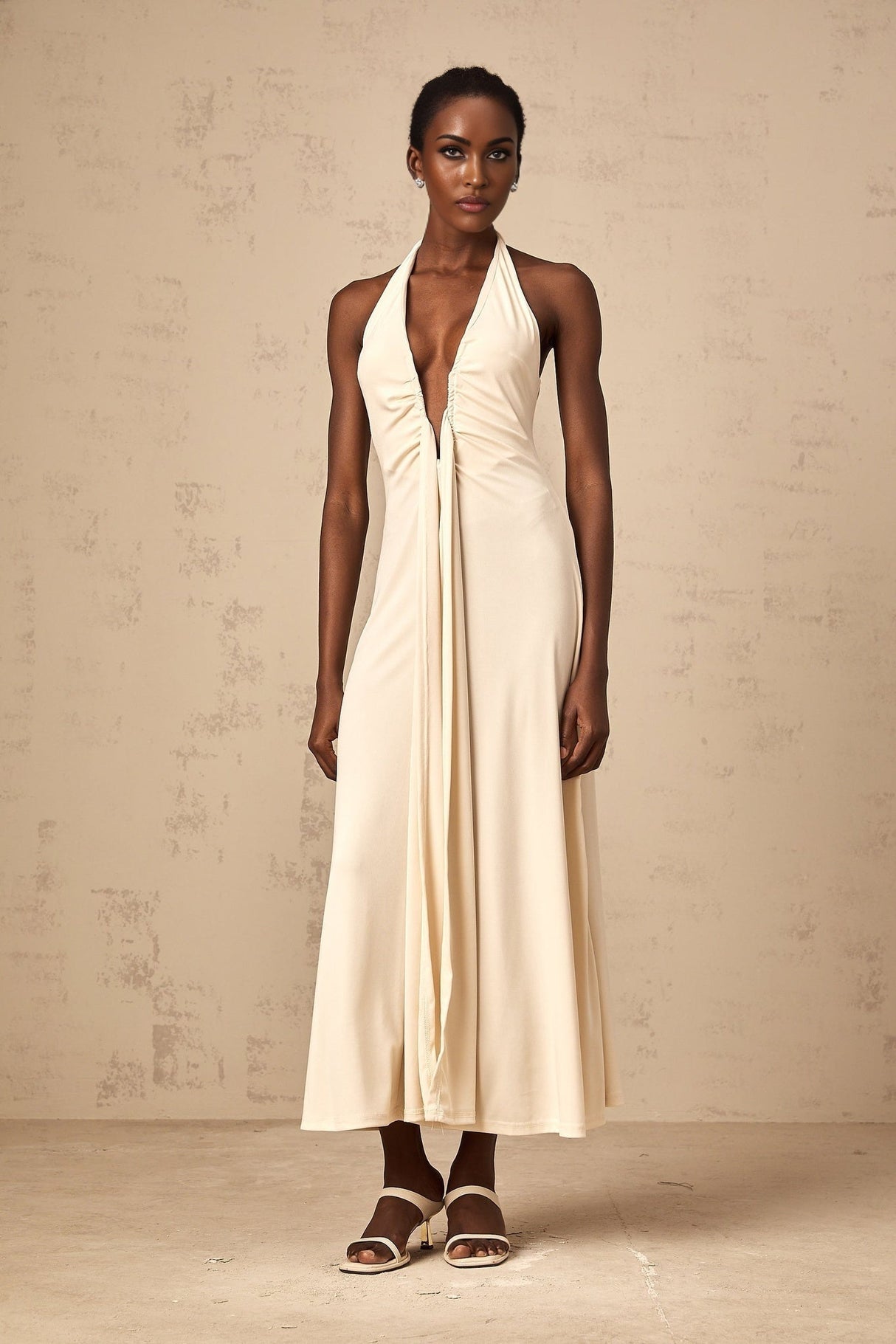 Woman wearing long white maxi dress with deep V neckline and draped details