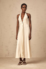Woman wearing long white maxi dress with deep V neckline and draped details