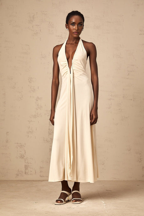 Woman wearing long white maxi dress with deep V neckline and draped details