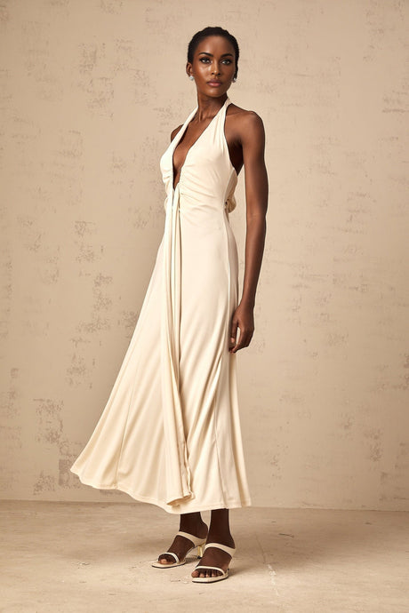 Woman wearing long white maxi dress with deep V neckline and draped fabric detail