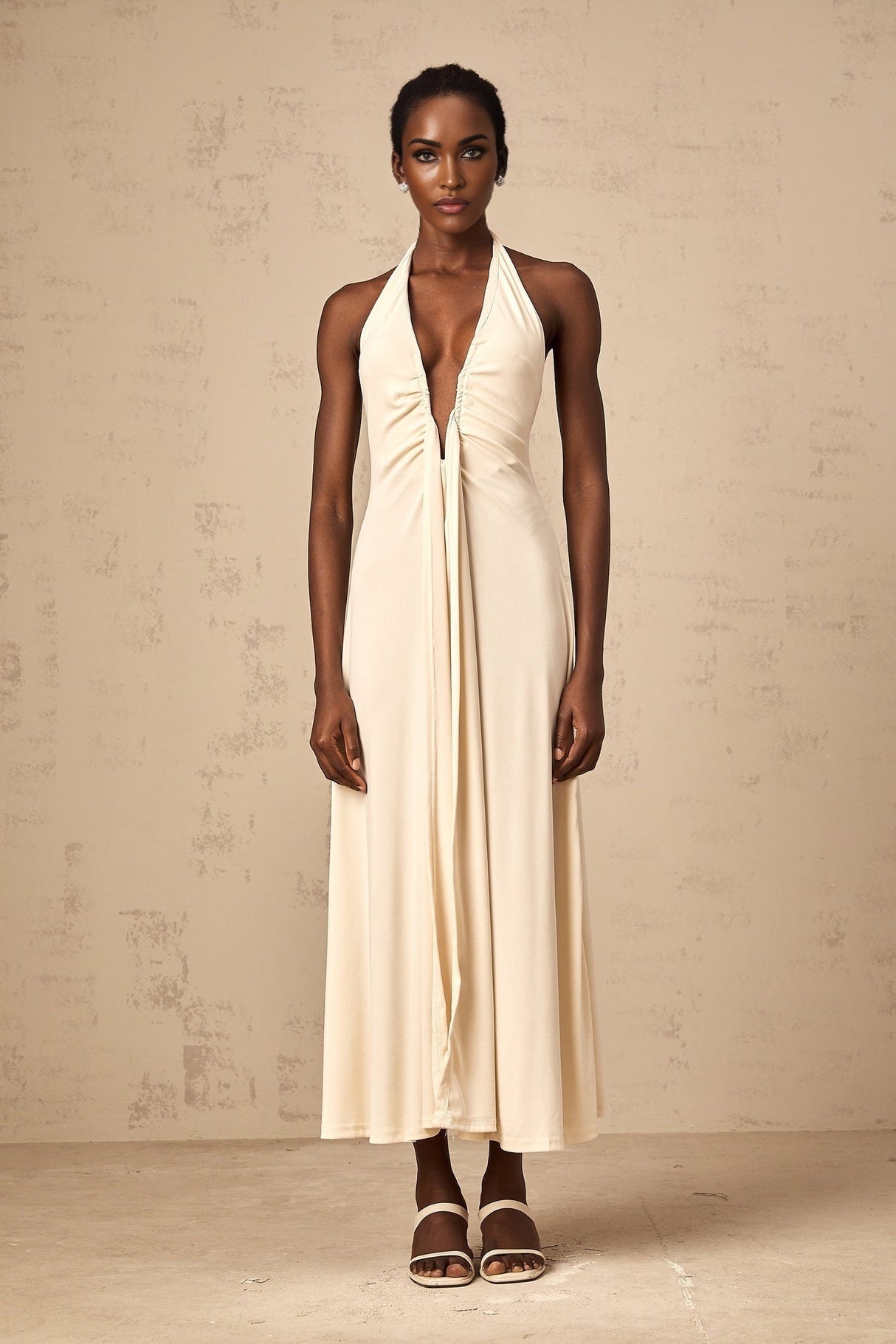 Woman wearing long white maxi dress with deep V neckline and draped fabric detail