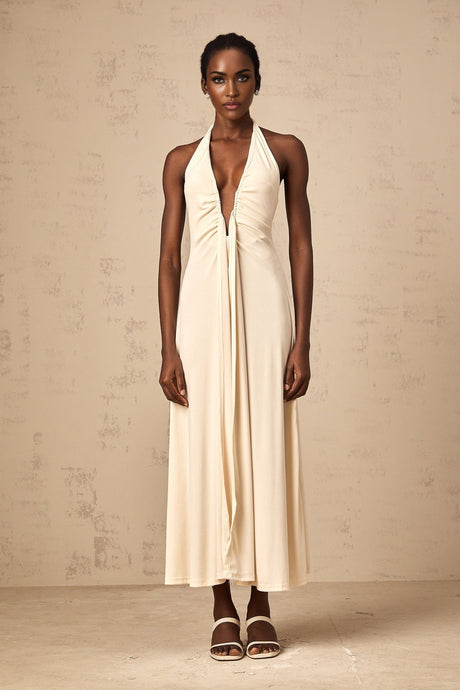 Woman wearing long white maxi dress with deep V neckline and draped fabric detail