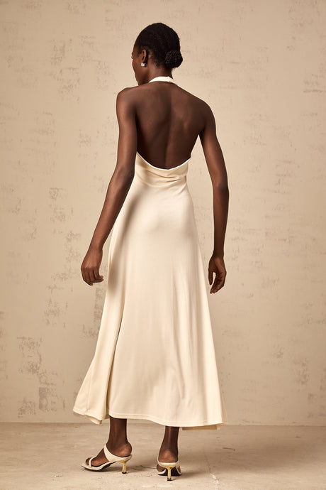 Woman wearing long white maxi dress with deep V neckline and draped fabric details