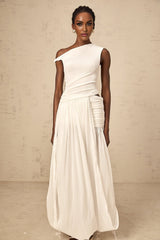Woman wearing long white maxi dress with single shoulder strap and shirred panel detailing