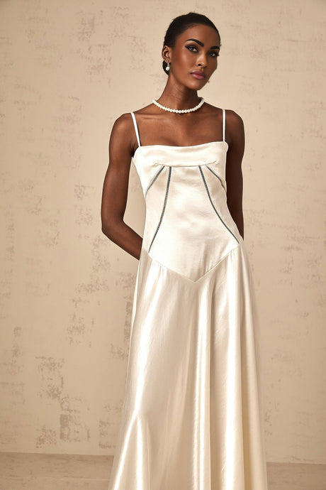 Woman wearing long white satin maxi dress with flared skirt and fitted bodice