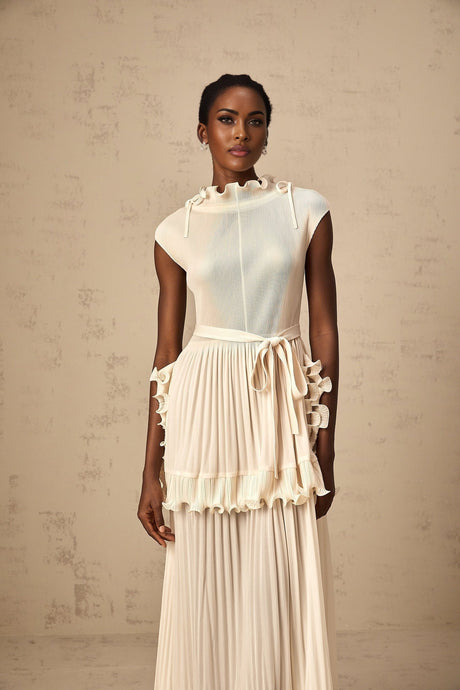 Woman wearing long white sleeveless maxi dress with ruffle details and pleated skirt