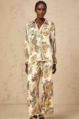 Woman wearing matching beige floral print shirt and trousers set with loose fit and neutral tones