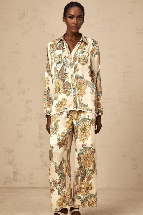 Woman wearing matching beige floral print shirt and trousers set with loose fit and neutral tones