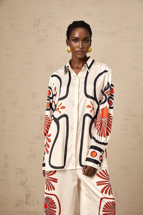 Woman wearing matching floral print shirt and trousers set in vibrant colors against plain background