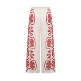 Woman wearing matching floral print shirt and trousers set in vibrant colors with Amaranta design