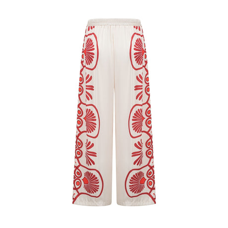 Woman wearing matching floral print shirt and trousers set in vibrant colors with Amaranta design