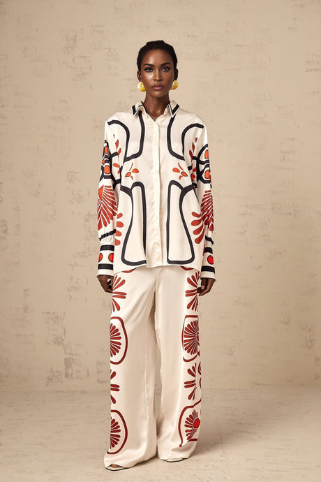Woman wearing matching floral print shirt and trousers set with vibrant colors and tropical pattern