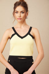 Woman wearing matching knit cardigan vest and trousers set in light color with contrasting dark trim Eloise style